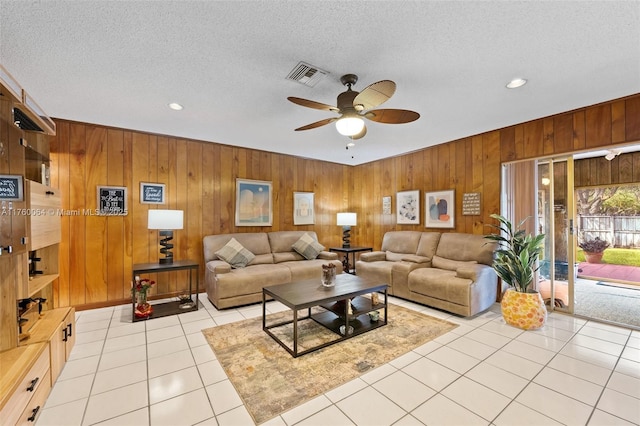 living area with light tile patterned floors, a ceiling fan, visible vents, and a textured ceiling