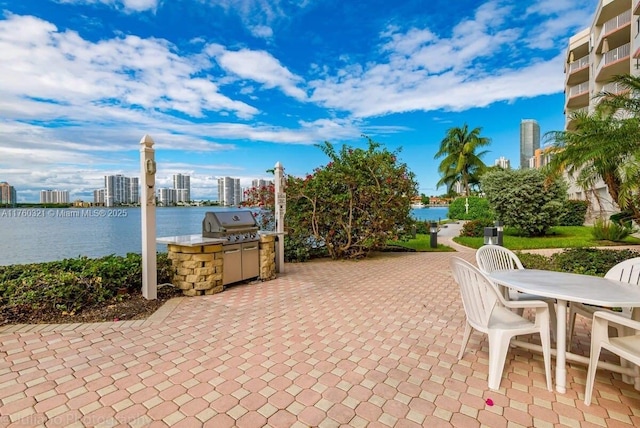 view of patio with area for grilling, a water view, and a city view