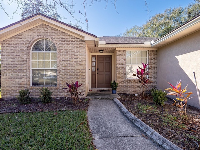 doorway to property with brick siding and stucco siding