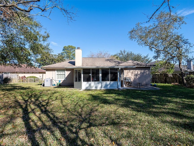 rear view of property with a lawn, a fenced backyard, a sunroom, and a chimney