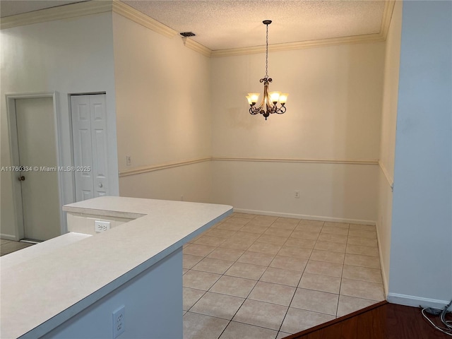 kitchen featuring ornamental molding, decorative light fixtures, a textured ceiling, light countertops, and a chandelier