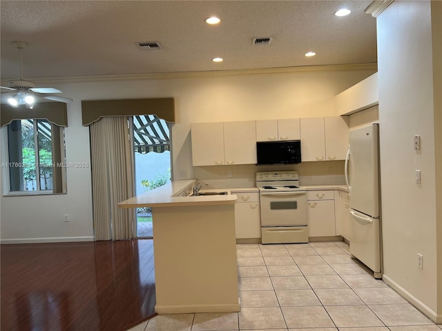 kitchen with a sink, visible vents, white appliances, and a peninsula