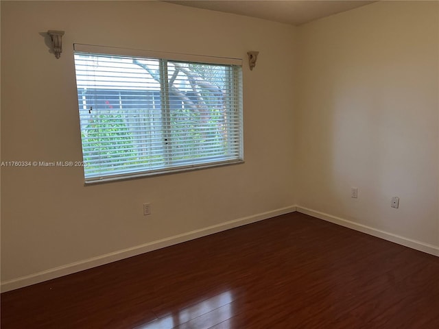 unfurnished room with baseboards and dark wood-style flooring