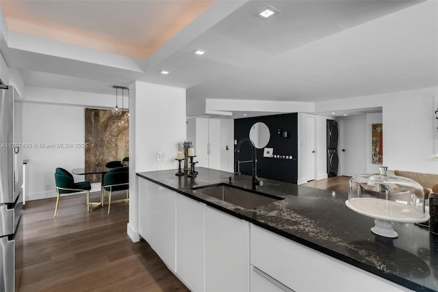 1000 Quayside Ter Unit 1812, Miami, FL 33138 - kitchen featuring a sink, dark wood-style floors, white cabinetry, stacked washing maching and dryer, and dark stone counters