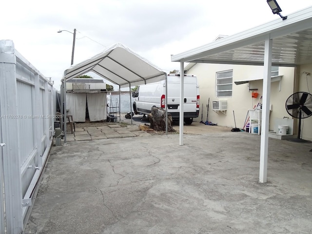 view of vehicle parking with a carport, a wall mounted AC, and fence