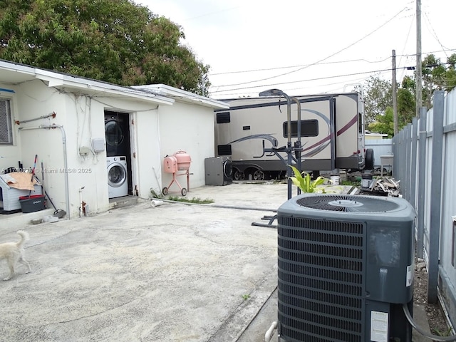 view of patio / terrace featuring cooling unit, fence, and stacked washing maching and dryer