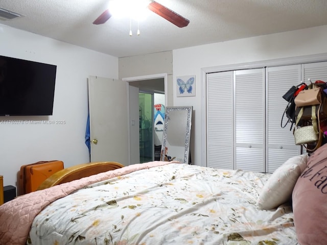 bedroom featuring a closet, visible vents, a textured ceiling, and ceiling fan