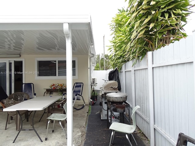 view of patio with grilling area, outdoor dining area, and fence