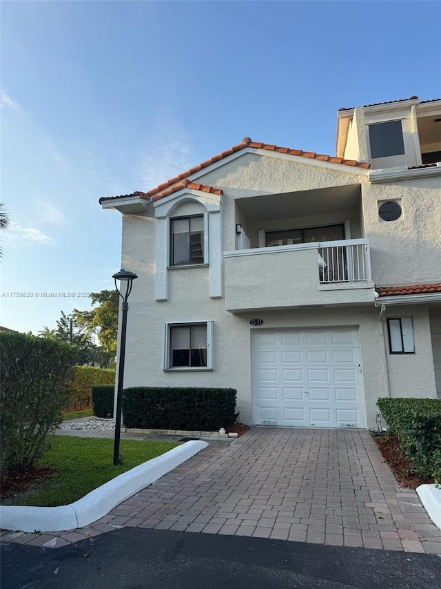 view of front of property featuring a tile roof, a balcony, decorative driveway, and stucco siding