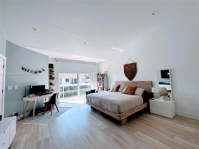 bedroom with baseboards, wood finished floors, and access to outside