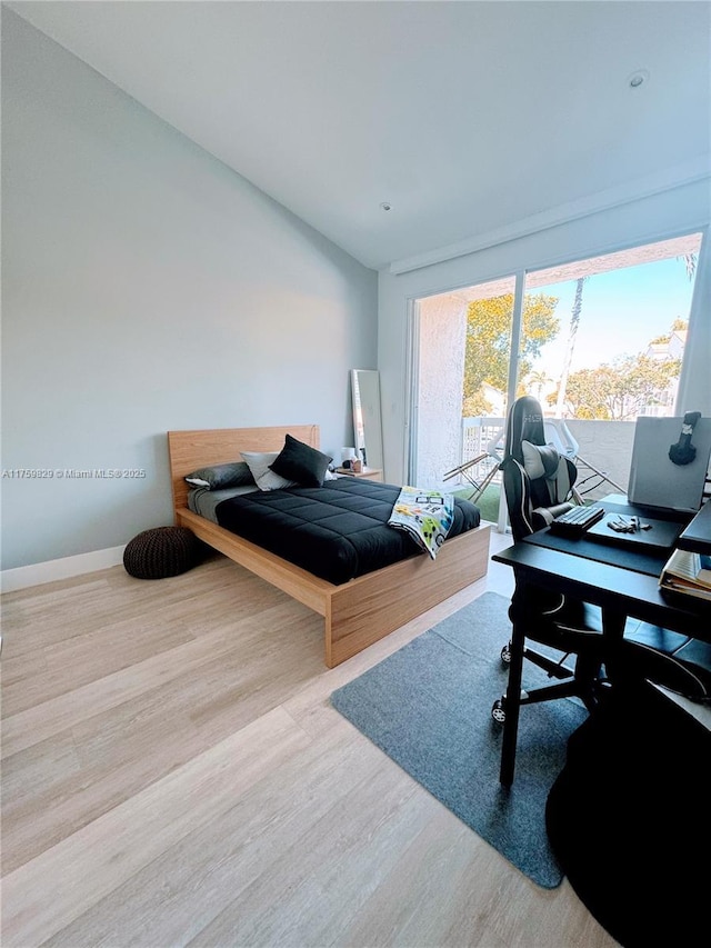 bedroom featuring baseboards, wood finished floors, and vaulted ceiling