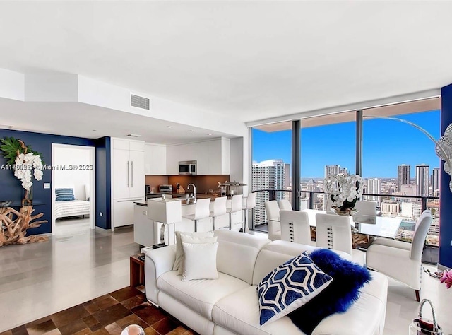 living area featuring visible vents, floor to ceiling windows, and a city view