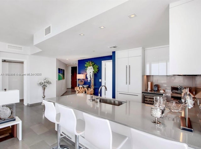 kitchen featuring a sink, a kitchen bar, a peninsula, white cabinetry, and modern cabinets