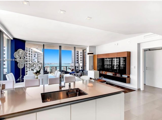 kitchen featuring a sink, expansive windows, lofted ceiling, and white cabinets