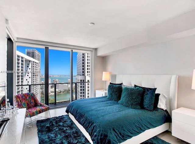 bedroom with a water view and expansive windows