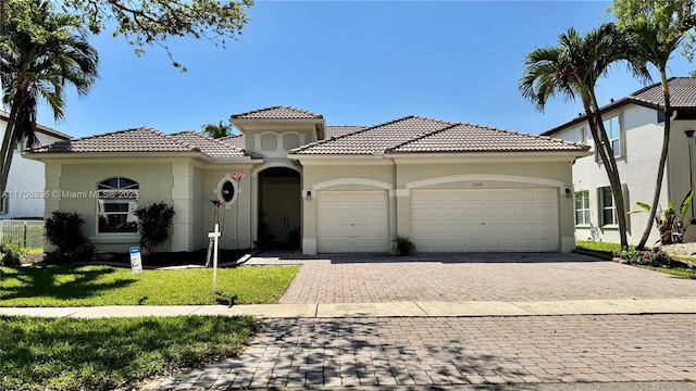 mediterranean / spanish house featuring stucco siding, a front lawn, decorative driveway, and a garage