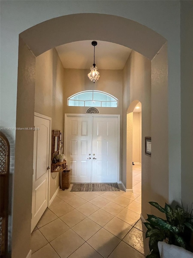 entryway with light tile patterned floors, arched walkways, and a towering ceiling