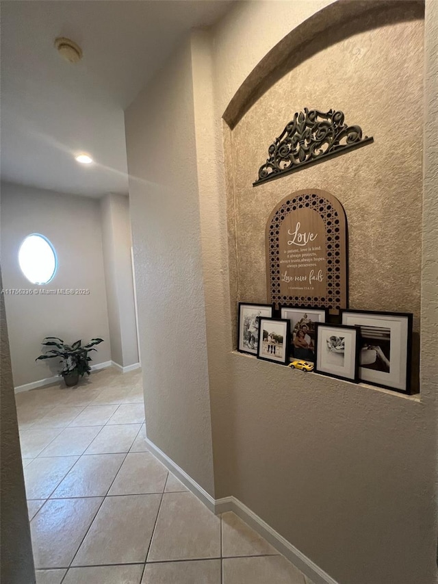 hallway with tile patterned floors and baseboards