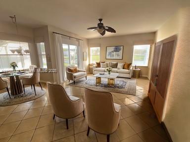 living room with light tile patterned flooring, a ceiling fan, and a wealth of natural light