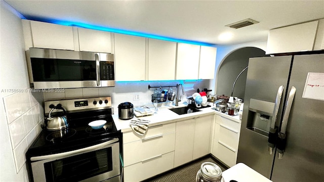 kitchen featuring visible vents, a sink, stainless steel appliances, light countertops, and tasteful backsplash