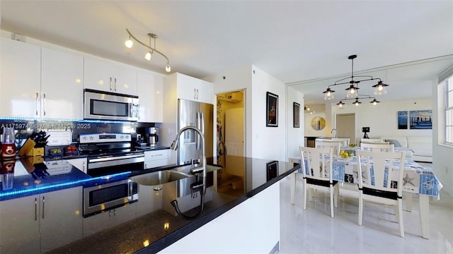 kitchen featuring a sink, dark countertops, decorative light fixtures, and stainless steel appliances