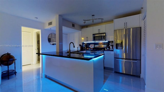 kitchen with dark countertops, visible vents, appliances with stainless steel finishes, white cabinets, and a sink