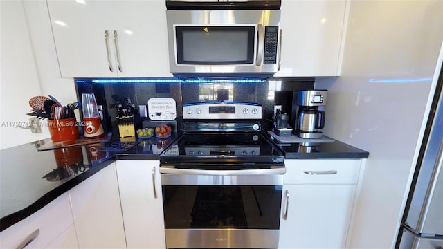 kitchen featuring white cabinetry, dark countertops, backsplash, and appliances with stainless steel finishes