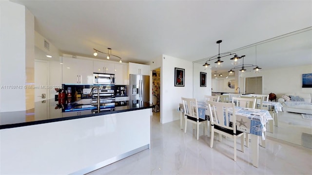 kitchen featuring visible vents, a peninsula, stainless steel appliances, hanging light fixtures, and white cabinetry