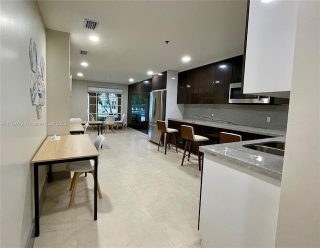 kitchen with visible vents, decorative backsplash, stainless steel appliances, modern cabinets, and a sink