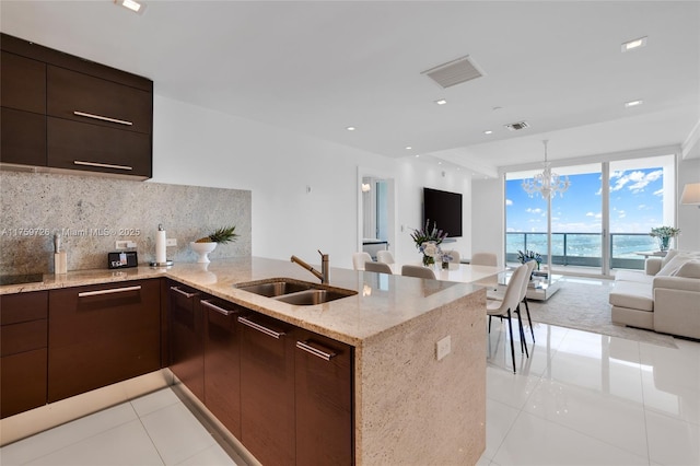 kitchen with modern cabinets, a sink, open floor plan, a peninsula, and decorative backsplash