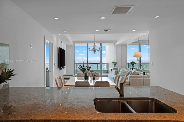 kitchen with visible vents, a notable chandelier, dark stone countertops, open floor plan, and floor to ceiling windows