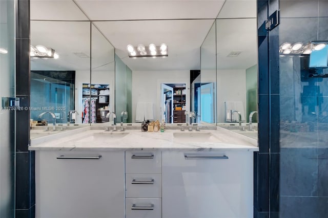 bathroom with double vanity, visible vents, a stall shower, and a sink