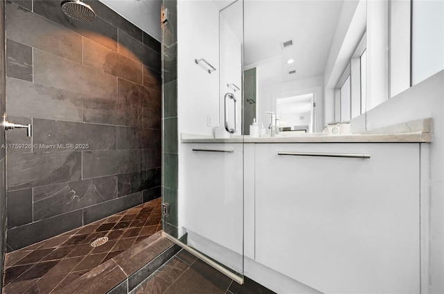 full bathroom featuring a tile shower, visible vents, recessed lighting, and vanity