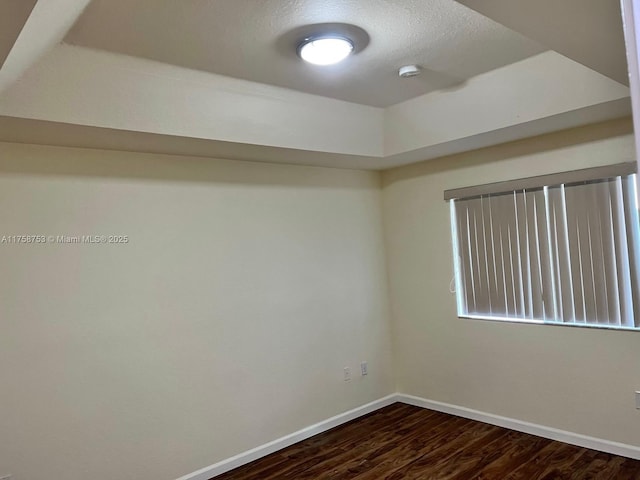 spare room featuring baseboards, a textured ceiling, and dark wood-style flooring