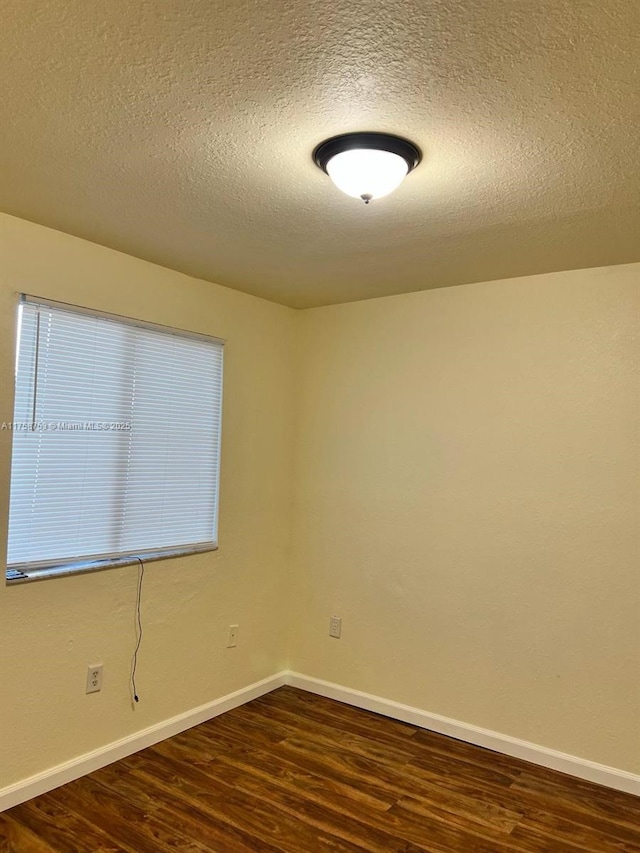 spare room featuring dark wood-style floors, baseboards, and a textured ceiling