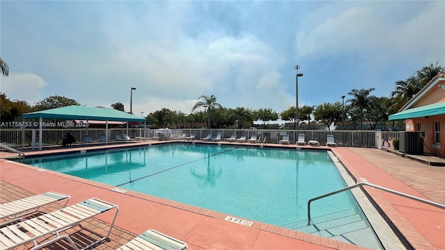 pool with central AC unit, fence, and a patio