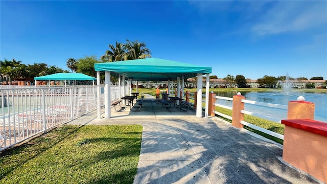 view of dock featuring a water view, fence, and a gazebo