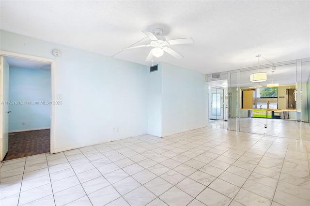 empty room with baseboards, visible vents, and ceiling fan