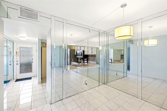 interior space with a sink, visible vents, and light tile patterned floors