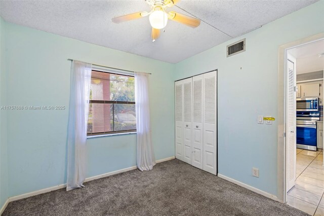 unfurnished bedroom featuring visible vents, baseboards, carpet flooring, a closet, and a textured ceiling