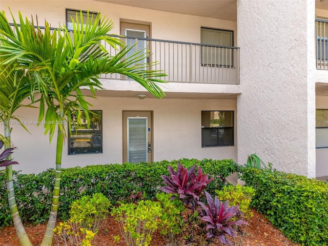 entrance to property with stucco siding and a balcony