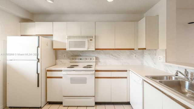 kitchen with white appliances, a sink, light countertops, a textured ceiling, and tasteful backsplash