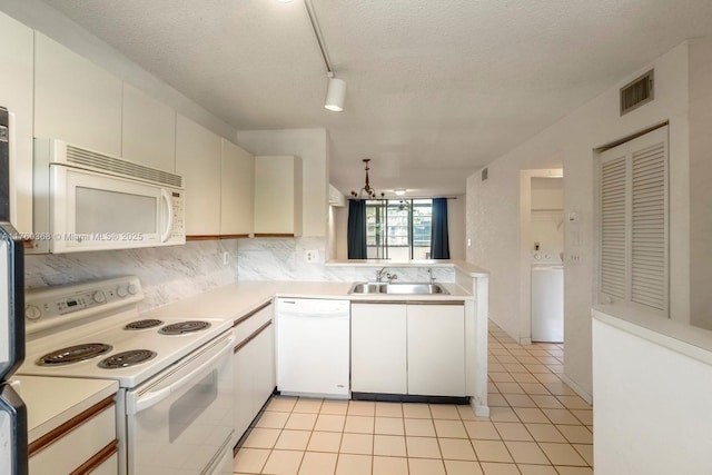 kitchen featuring visible vents, light tile patterned flooring, white appliances, washer / clothes dryer, and a sink