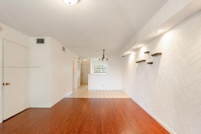 empty room with visible vents, a textured ceiling, and wood finished floors