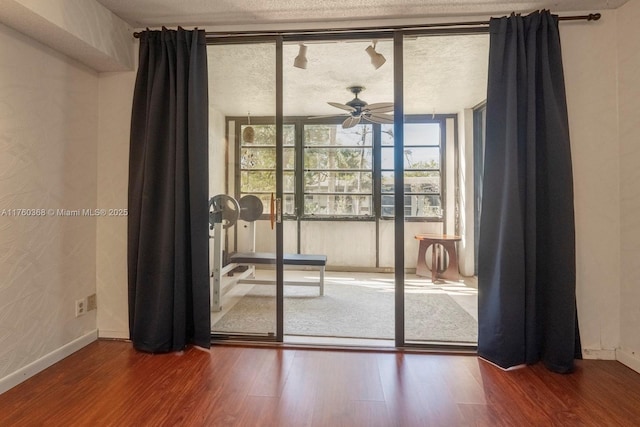 doorway to outside featuring ceiling fan, baseboards, a textured ceiling, and wood finished floors