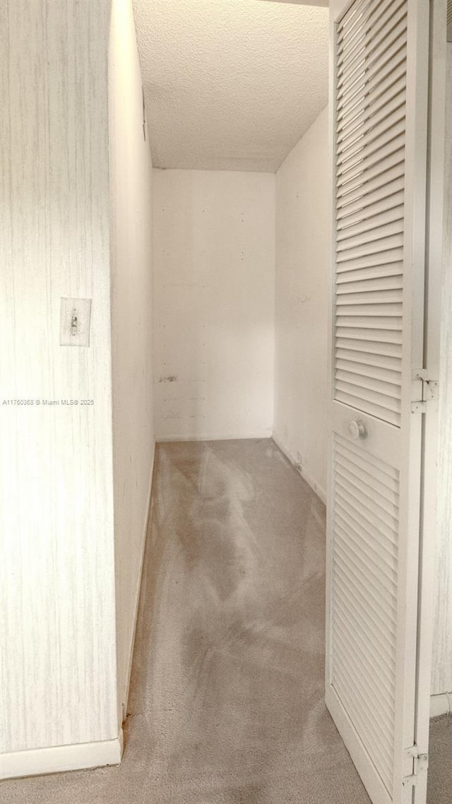 hallway featuring carpet and a textured ceiling