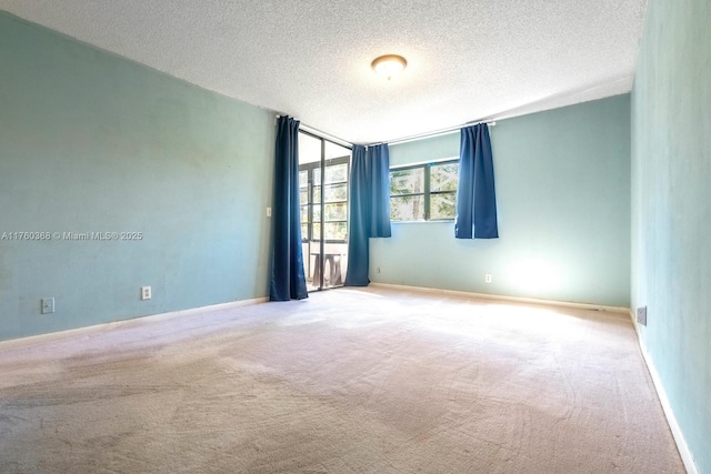 empty room featuring baseboards, carpet floors, and a textured ceiling