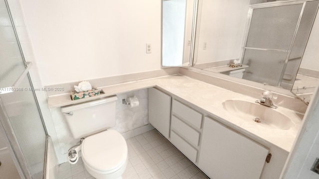 bathroom featuring a shower with shower door, toilet, vanity, and tile patterned flooring