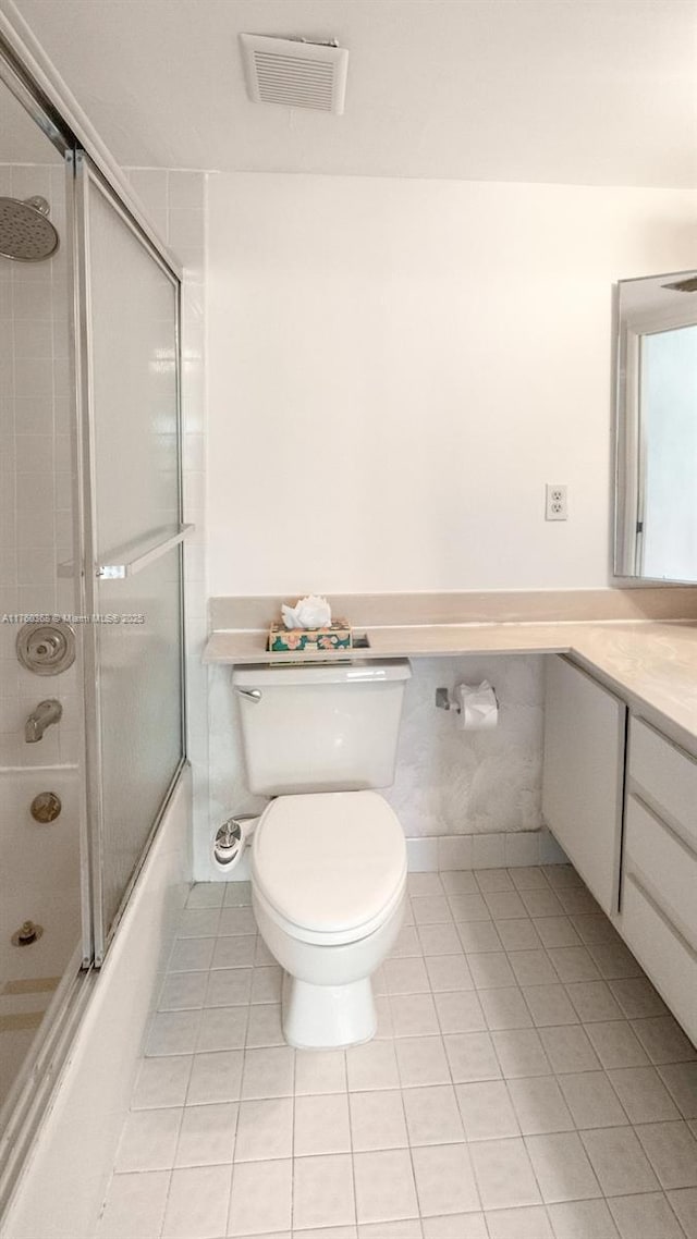 full bath featuring visible vents, toilet, shower / bath combination with glass door, tile patterned flooring, and vanity