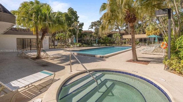 pool with a patio area and a hot tub